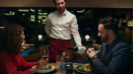 Sommelier waiter pour wine to romantic couple in restaurant. Lovers enjoy drink. - Powered by Adobe