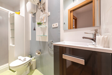 Bathroom with dark wood furniture, frameless glass mirror over white porcelain sink and shower...