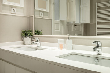 One-piece washbasin with two sinks and two taps in a bathroom with a built-in mirror in the wall and a white towel-drying radiator