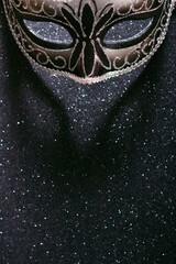 Elegant black carnival mask on a dark background with sequins closeup with copy space