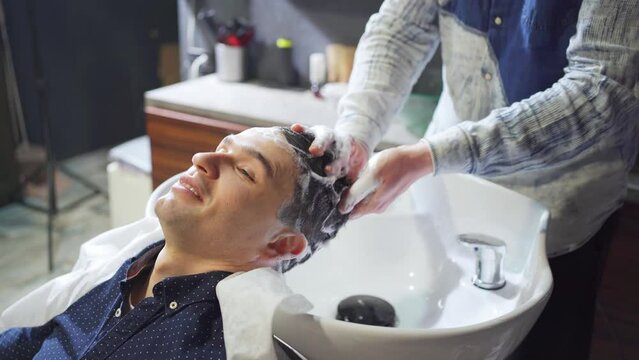 a brunet man washes hair with a hairdresser in a barbershop. 