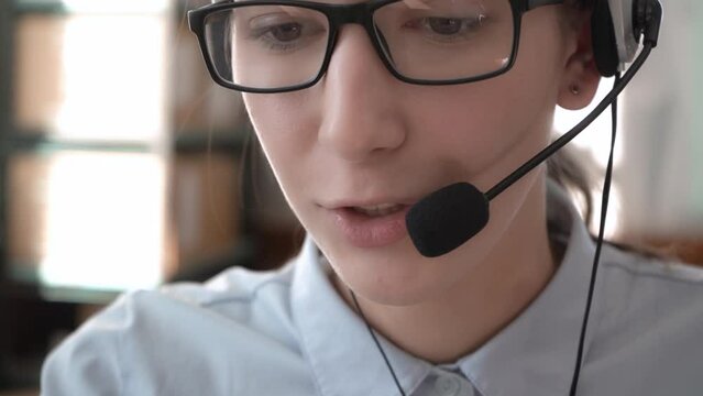 A girl in headphones with a headset conducts consultations. Call center. 