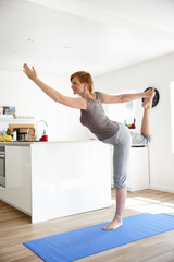 Fototapeta na wymiar Stretching towards wellness. Shot of an attractive woman doing yoga in her home.