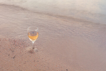 A glass of white wine by the sea. Sandy beach, summer day.