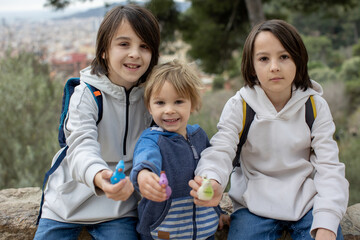 Children, cute boys, playing with ceramic clay whistle in the form of bird, souvenir from park Guell in Barcelona