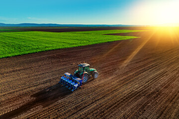 Farmer with tractor seeding crops at field