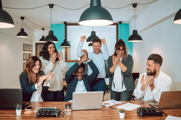 Multiracial coworkers celebrating victory at table