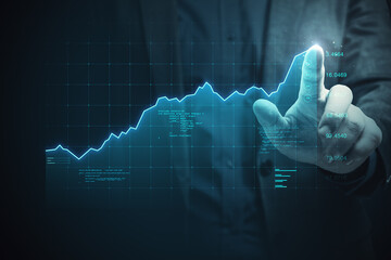 Close up of businessman hand pointing at glowing digital business chart grid. Success, money,...