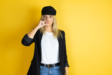 Beautiful woman wearing casual white t-shirt and a cap over isolated yellow background mouth and...