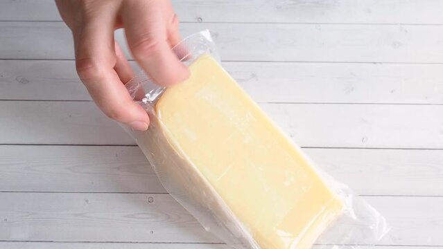 Soft cheese in vacuum packaging is placed on the table. A piece of cheese is packed for long-term storage and transportation.