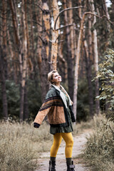 Photo of a girl dressed as a national American. Walk and rest in the summer forest. Entertainment. The game. Fun. Wear a jacket, khaki dress and bright yellow tights. Happy woman.