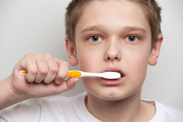 Boy's face and hand holding a toothbrush near his mouth. Dental and oral hygiene