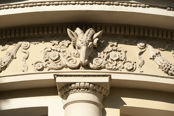 A part of the facade of an old building with beautiful stucco decoration and bas-relief head of the...