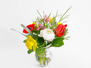 Ein kleiner Frühlingsblumenstrauß mit Anemonen, Tulpen, Narzissen und Trollblumen in einer Vase