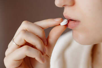 Beautiful young woman taking pills, closeup. Sick ill woman holding antidepressant painkiller...