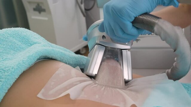 Beautician applying cryolipolysis treatment in beauty salon.	
