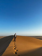 Fototapeta na wymiar Young man walks along sandy dunes. Dune 17 in Namibia. 