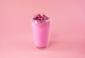 Pink rose milk with rose petals in a double walled glass. Healthy drink moon milk.