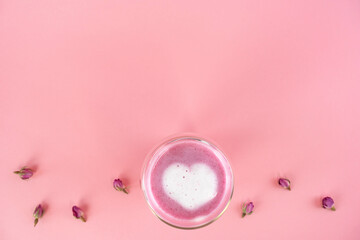 Pink rose milk with rose petals. Heart-shaped foam in a glass of moon milk. Healthy drink. Top view. Copy space.