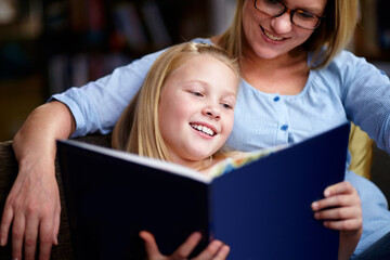 Reading exercises the brain. A cute young girl sitting next to her mother while they read a book.