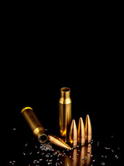 Obraz na płótnie Canvas Close-up of disassembled rifle cartridges. Bullet isolated on black background with reflexion. Granulated gunpowder.