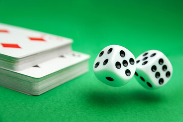 Dice on a green background with a deck of cards.