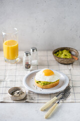 Breakfast toast with avocado and sunny side up egg. Healthy breakfast with avocado toast and orange juice