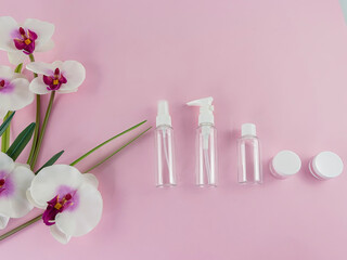 Empty Beauty Bottles. Isolated.Empty plastic bottles on a pink background with realistic fake orchids on the left. Copy Space.
