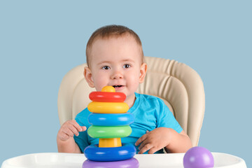 Smiling toddler 12-17 months old smiles by building a pyramid tower of colored rings for the first...