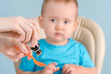 Mom gives the newborn medicine on a spoon