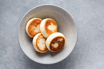 Syrniki, cottage cheese fritters on grey ceramic plate, top view. Breakfast food