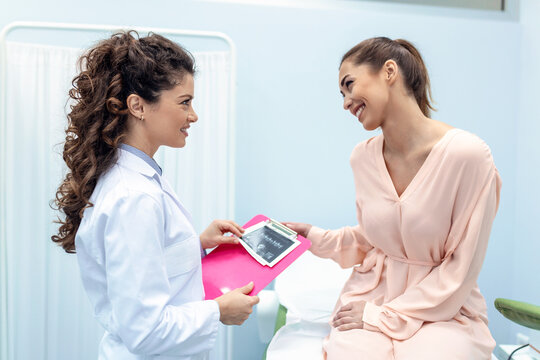 Gynecologist showing a picture with ultrasound to a young woman patient, explaining the features of women's health during a medical consultation in the office