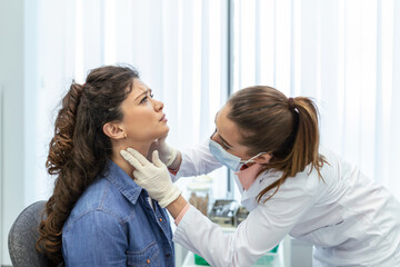 Obraz na płótnie Canvas medicine, healthcare and medical exam concept - doctor or nurse checking patient's tonsils at hospital. Endocrinologist examining throat of young woman in clinic