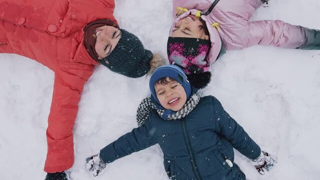 Kids making a snow angel lying on the snow