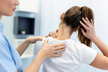 Woman doctor osteopath in medical uniform fixing woman patients shoulder and back joints in manual...