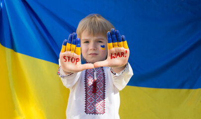 boy in national Ukrainian clothes put his hands forward, inscription STOP War against background of...