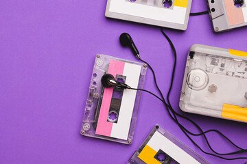 Cassette player with earphones and cassette tapes on purple background.