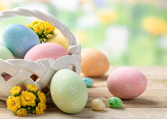 Easter eggs and flowers in a basket and on a wooden table