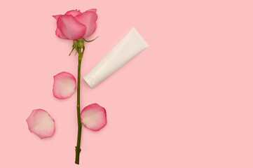 Rose branch and rose petals. Cosmetic cream. On a pink background.