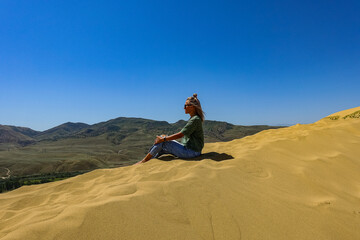 A girl on the sand dunes of Sarykum. The desert in Dagestan. Russia. 2021.