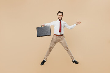 Fototapeta na wymiar Full body winner young successful employee business man corporate lawyer in white shirt red tie glasses work in office jump run fast hold case spread hands isolated on plain beige background studio.