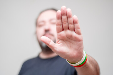 An unshaven man with bracelets in the colors of the Bulgarian flag holds his hand in front of him...