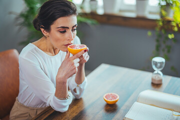 Sick woman trying to sense smell of half fresh orange, has symptoms of Covid-19, corona virus...