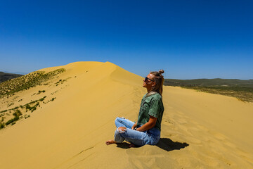 Fototapeta na wymiar A girl on the sand dunes of Sarykum. The desert in Dagestan. Russia. 2021.