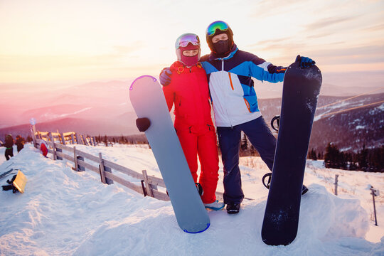 Happy couple man and woman snowboarders background sunset ski resort. Concept friends travel love winter