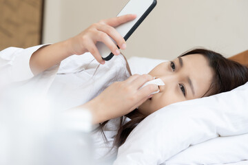 Asian woman feeling sick have a headache, coughing because of Coronavirus Covid-19 with using smartphone. Protection and recovery from the illness quarantine at home, Stay at home.
