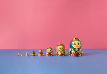 Russian dolls also known as matryoshka or babushka stacked on a pink and blue background. Minimal...