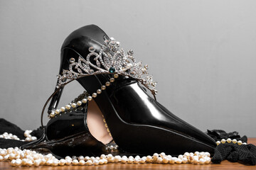 black patent leather women's shoes, pearls and diadem on the table