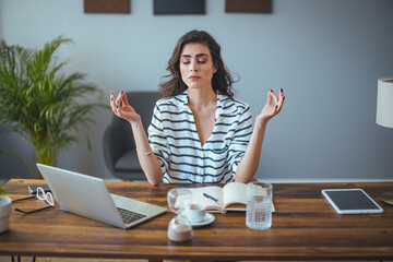 Mindful calm indian young business woman meditate at work desk with eyes closed, healthy hindu girl...
