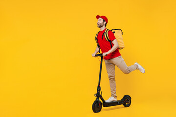 Full size side view delivery guy employee man in red cap T-shirt uniform workwear work as dealer courier ride electric kick scooter hold thermal food bag backpack isolated on plain yellow background.